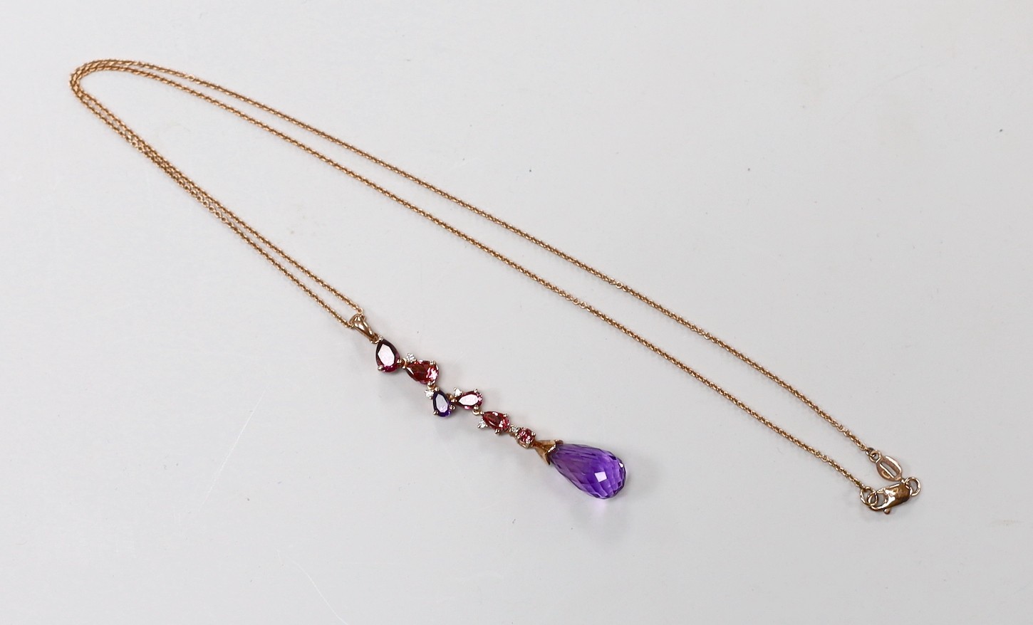 A modern 9ct gold, garnet, topaz, amethyst and diamond chip set drop pendant necklace, pendant 46mm, chain 46cm, gross weight 4.7 grams.